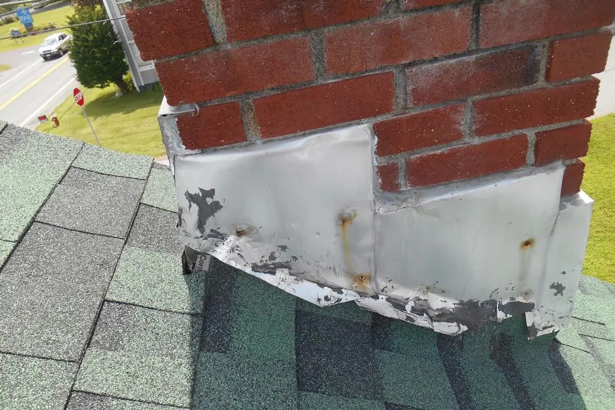 Poorly formed flashing where a chimney passes through a shingle roof