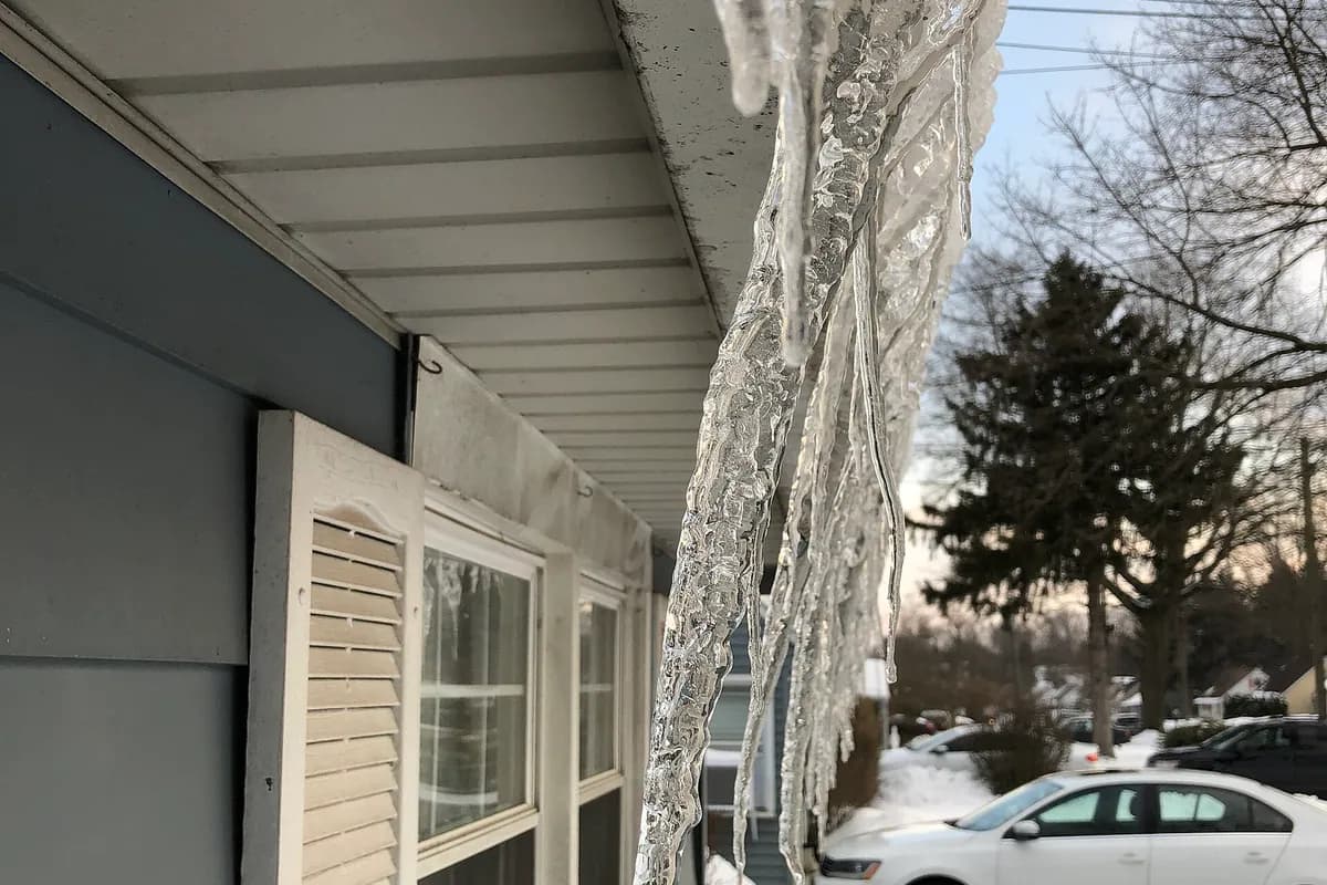 A rain gutter along a New Jersey roof edge with icicles hanging from it in winter